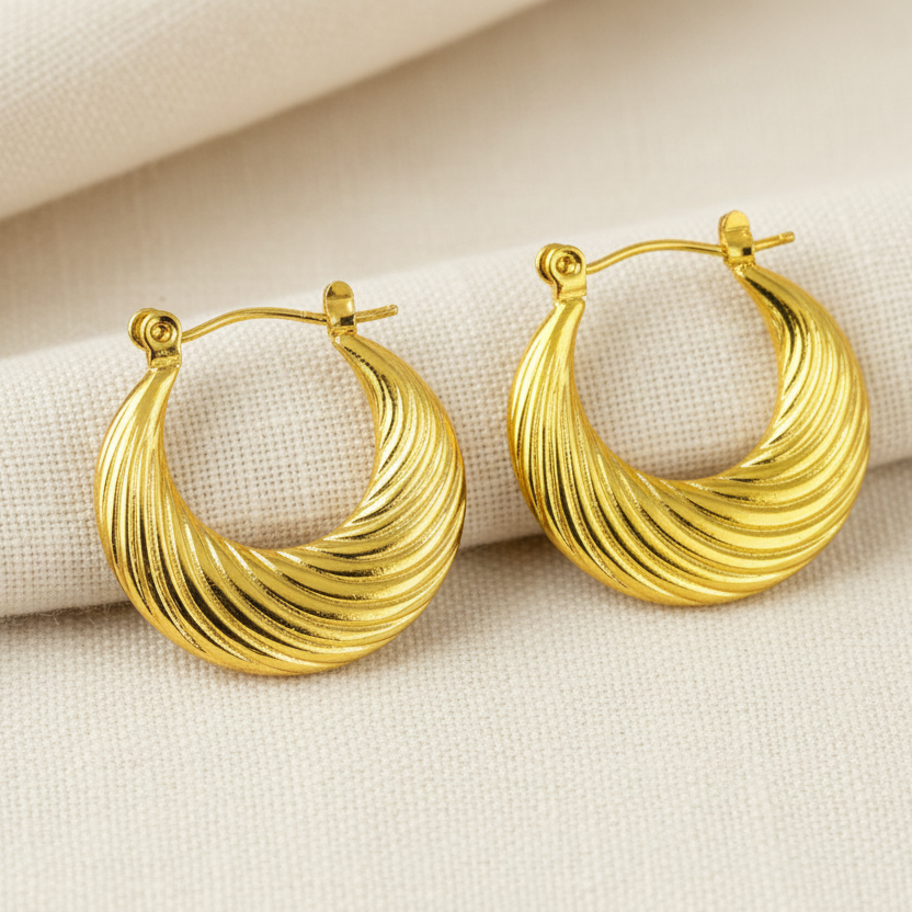Pair of gold hoop earrings on a beige fabric background