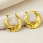 Pair of gold hoop earrings on a beige fabric background